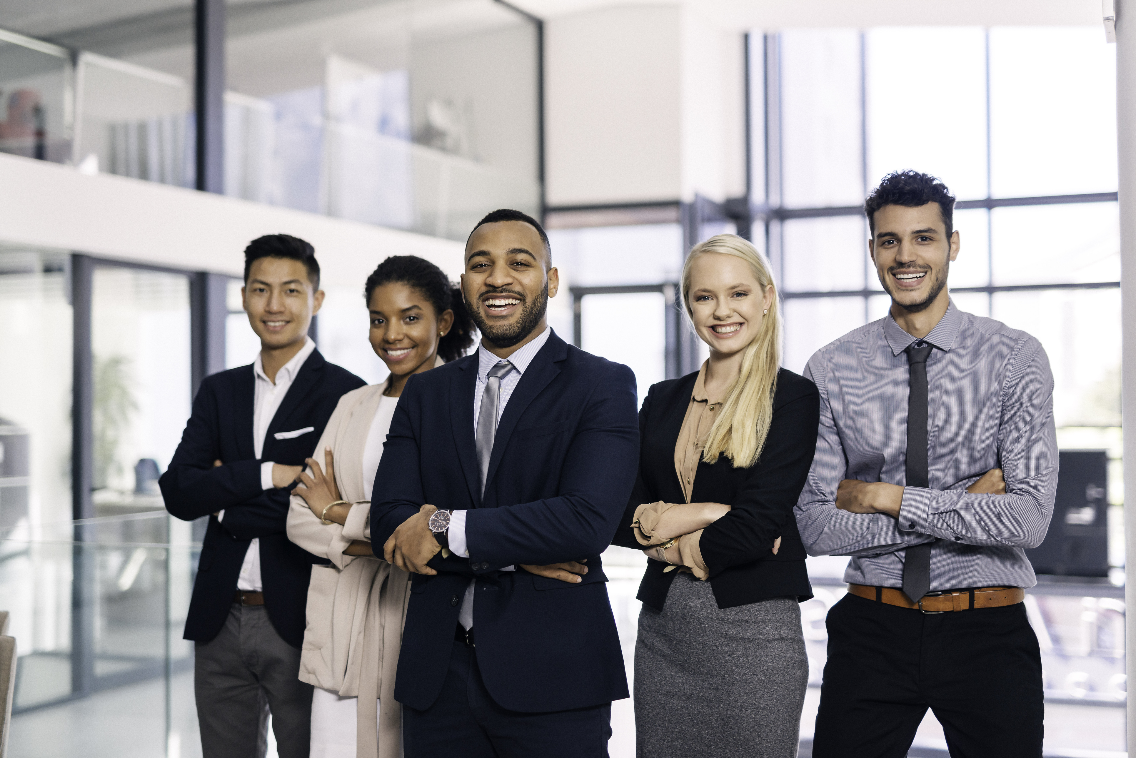 Diverse group of smiling professionals posing in a modern office setting.